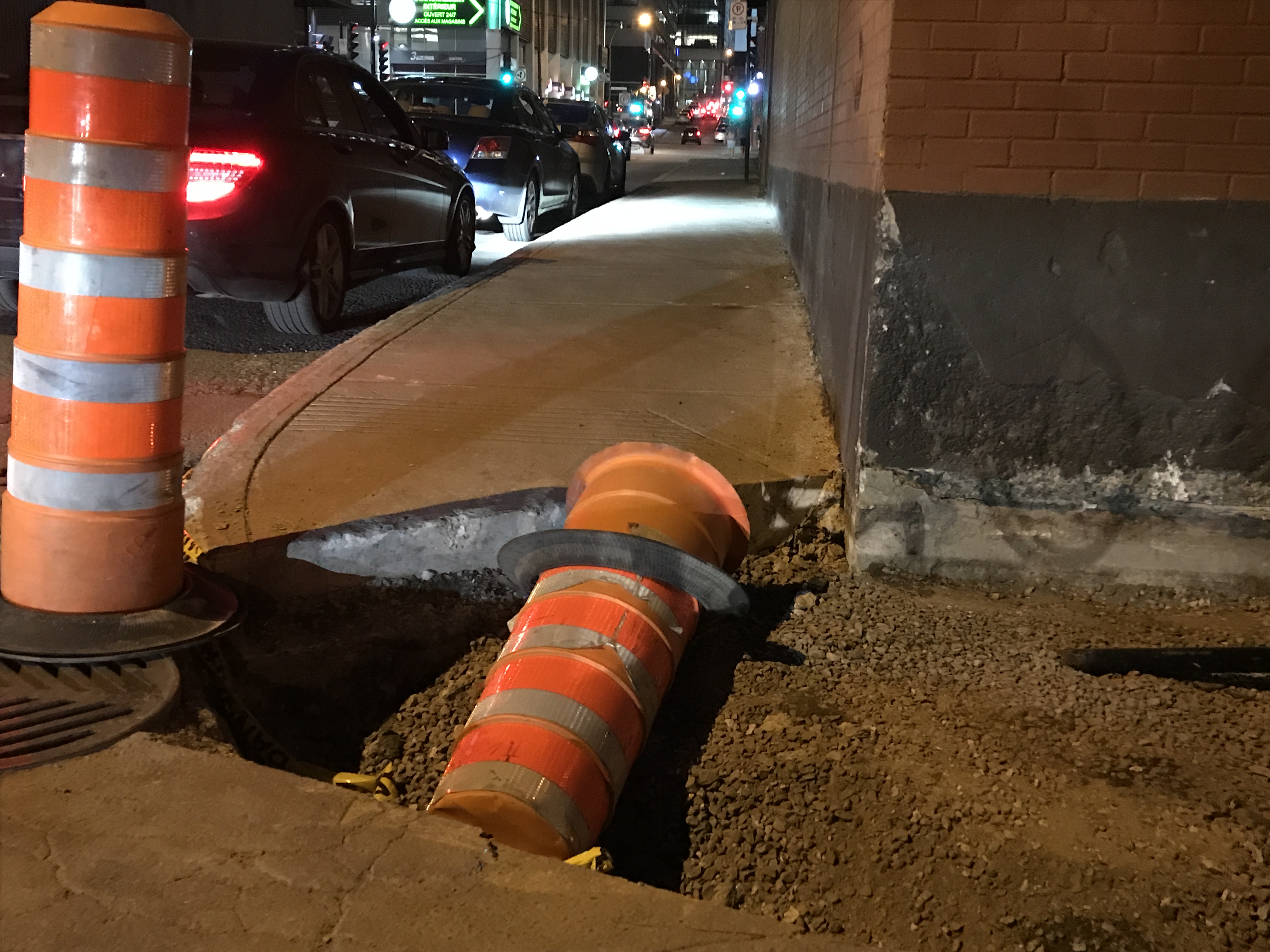 Curb cut on a badly lit corner at night, dug up with construction.