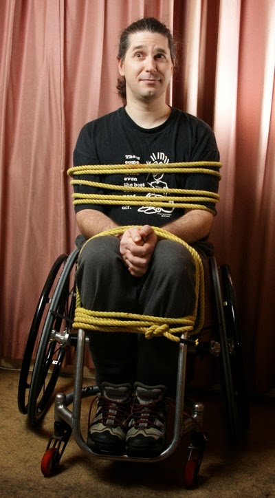 Photo of a man tied with thick rope to his wheelchair