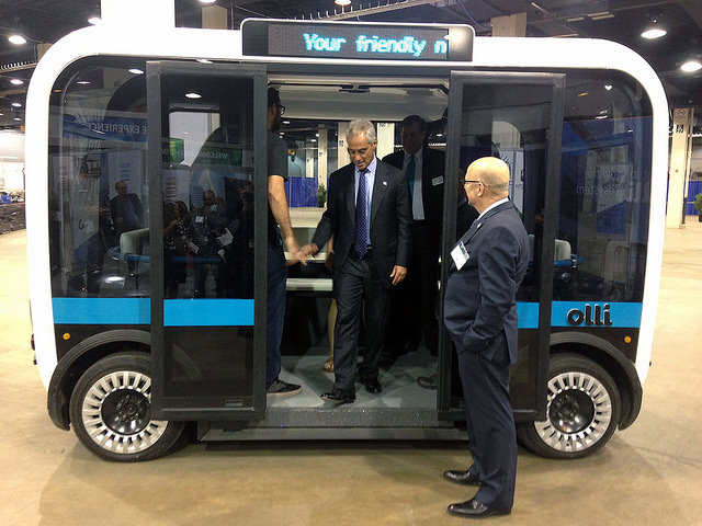 The Olli self-driving bus shown from the side with door opened and a man about to get out of it.